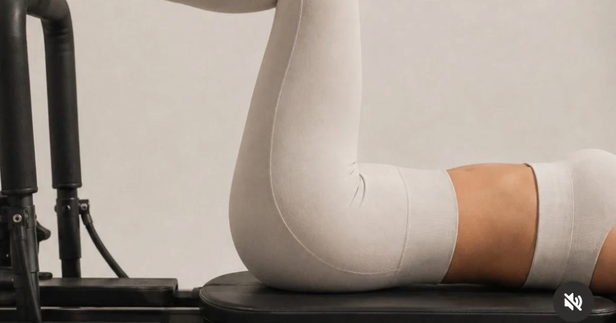 Client in a supine position on a Lagree machine, knees drawn in